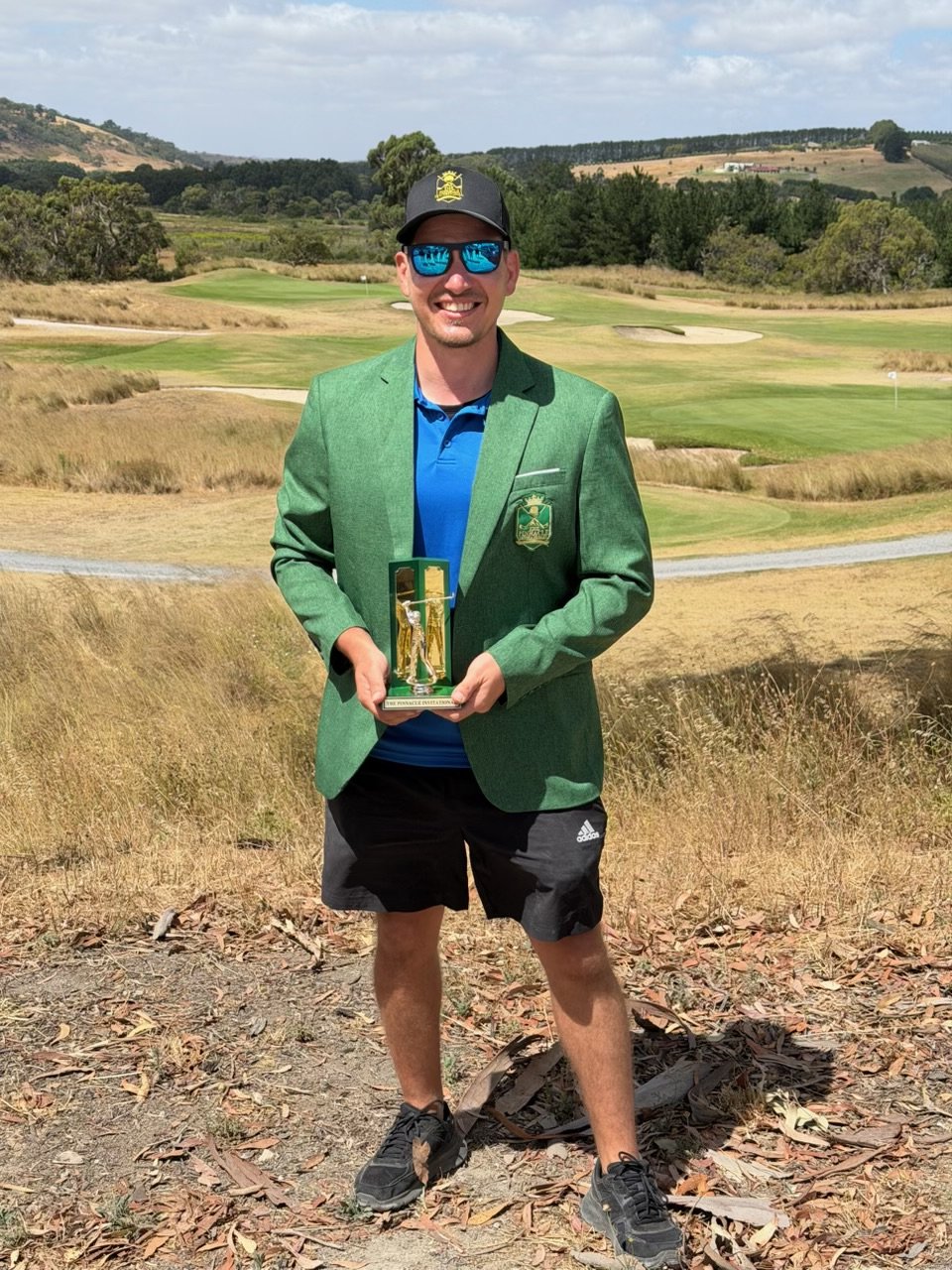 Simon Nedelkovski wearing the Pinnacle Green Jacket and holding the inaugural trophy